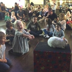 The birthday child beams with happiness holding Snowy the rabbit while friends laugh and clap in Burton Upon Trent.