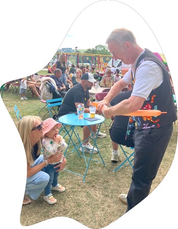 Children enjoying colourful balloon animals and balloon twisting at an event by Magic Stuart.