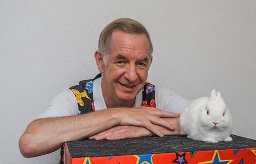 Photograph of Magic Stuart smiling with his magical rabbit Snowy.
