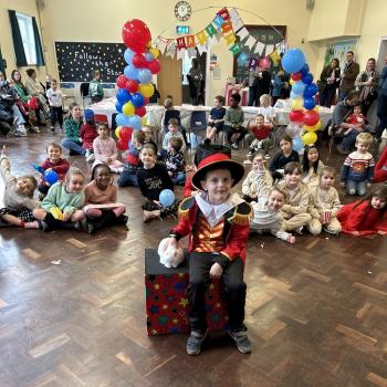 A group of children laughing and clapping during a birthday party show in Allestree