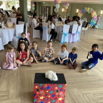 A group of children laughing and clapping during a birthday party show in Arnold