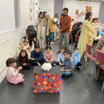 A group of children laughing and clapping during a birthday party show in Belper