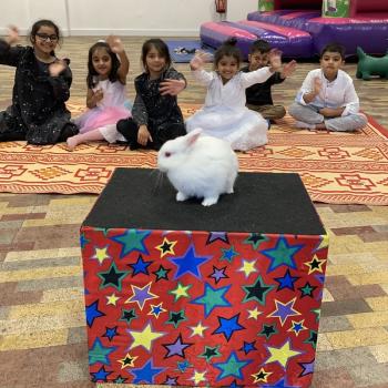 A group of children laughing and clapping during a birthday party show in Bingham