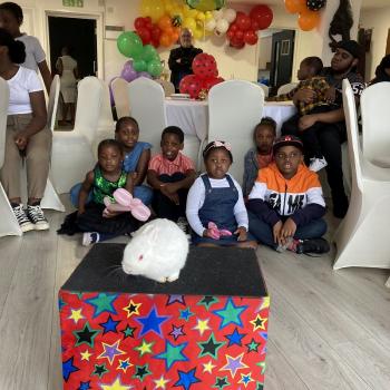 A group of children laughing and clapping during a birthday party show in Castle Donington
