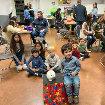 A group of children laughing and clapping during a birthday party show in Chilwell