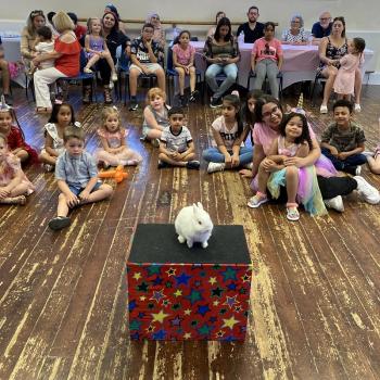 A group of children laughing and clapping during a birthday party show in Derby