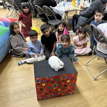 A group of children laughing and clapping during a birthday party show in Leicester