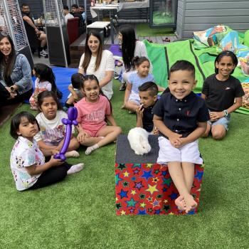 A group of children laughing and clapping during a birthday party show in Loughborough