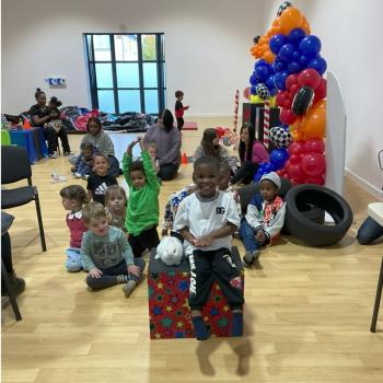 A group of children laughing and clapping during a birthday party show in Swadlincote