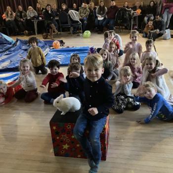 A group of children laughing and clapping during a birthday party show in Uttoxeter