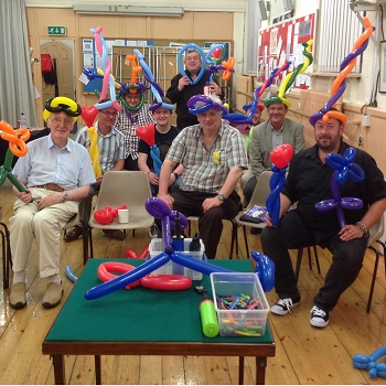 Community group proudly holding their balloon creations at the end of a classroom workshop by Magic Stuart
