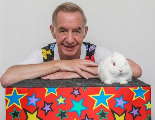 Local newspaper clipping of Snowy the rabbit with children at a magic show.